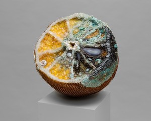 Kathleen Ryan, Bad Lemon (Seed), 2024. Agate, amber, amazonite, amethyst, aquamarine, citrine, labradorite, turquoise, tektite, magnesite, jasper, jade, dolomite and fuchsite, prehnite, snowflake obsidian, quartz, mother of pearl, glass, and steel pins on coated polystyrene, 18 × 17 ½ × 18 ½ inches (45.7 × 44.5 × 47 cm) © Kathleen Ryan. Photo: Lance Brewer